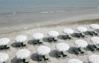 Elegant white parasols and green sun loungers on Italian beach