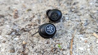 The JLab JBuds Air Pro wireless earbuds resting on a concrete surface