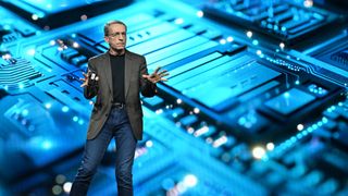 Intel CEO Pat Gelsinger giving a talk on stage in front of a large image of a CPU