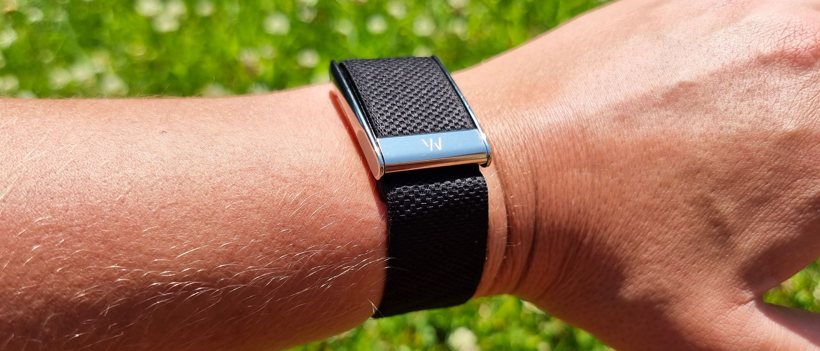 A close-up picture of our reviewer wearing the Whoop MG fitness tracker in the park