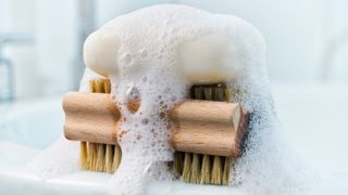 two cleaning products, Soap, foam and brush on bathroom sink