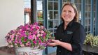 Woman smiling next to pot of pink calibrachoa flowers
