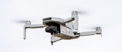 A white Potensic atom drone with black camera is in flight.