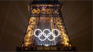 The five Olympic rings in front of the Eiffel Tower at night