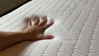 REM-Fit Hybrid 1000 mattress with tester's hand resting on it