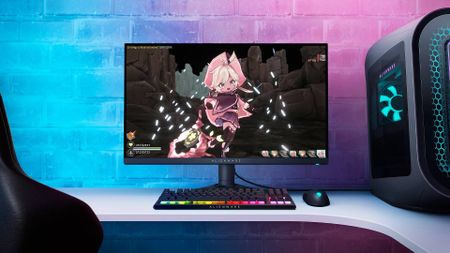 Alienware AW2724DM gaming monitor next to Aurora R16 PC on desk with RGB keyboard and mouse featuring Witch Spring R artwork on screen.