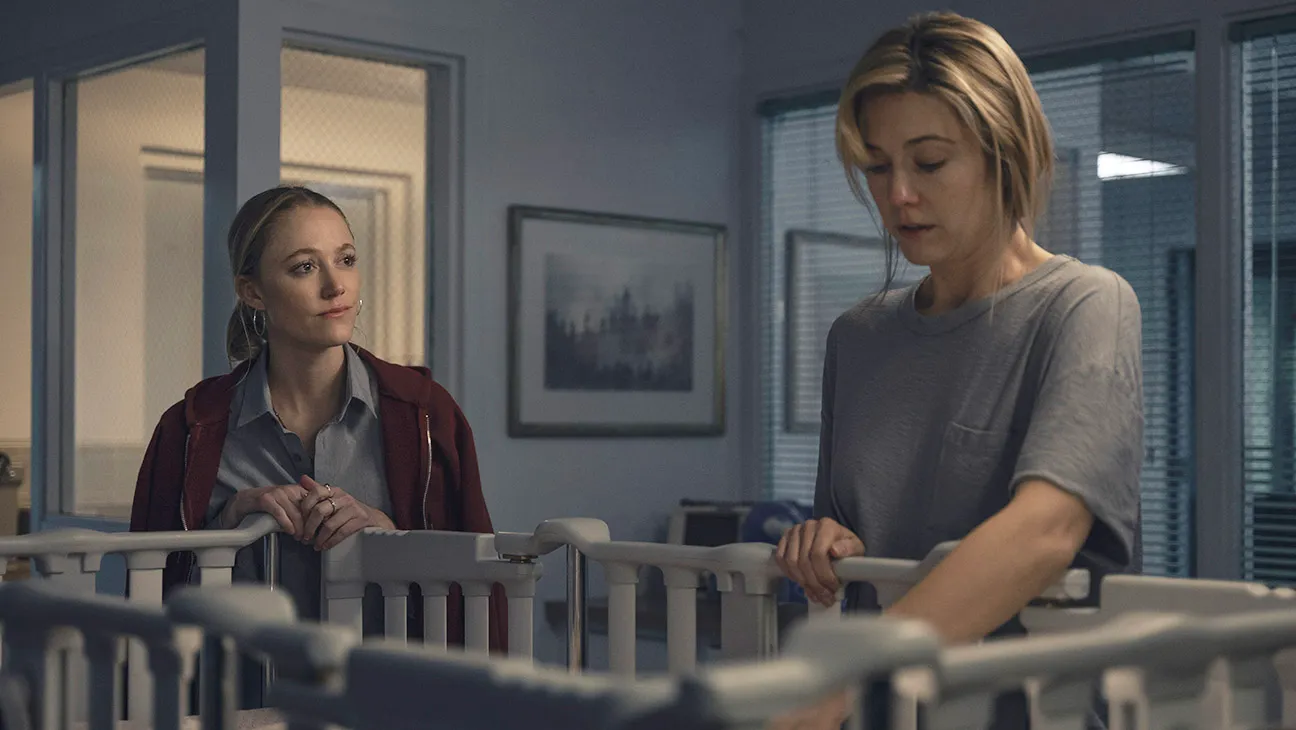 maika monroe and mary elizabeth winstead look at a crib in a dark room in the movie the hand that rocks the cradle