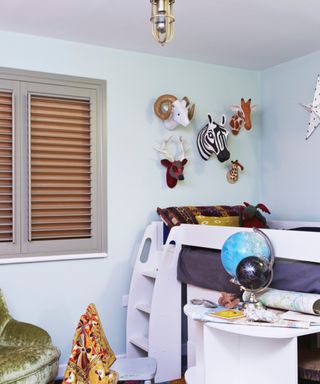 children's bedroom with bunk beds, shutter, globes, animal heads on wall, chairs