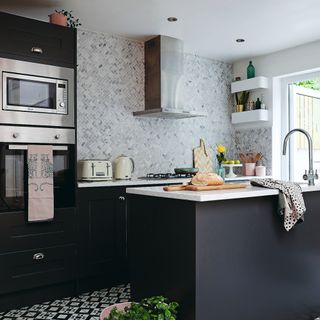 Kitchen with dark cabinetry and island, white countertops, sink