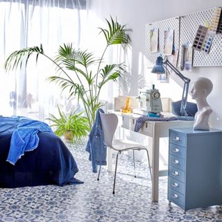 Blue toned bedroom with tall kentia plant in pot