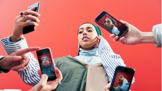 Young woman surrounded by smartphones.
