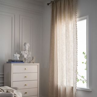 beige tasseled curtain panel over window