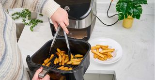 Person using tongs with an air fryer to show the best air fryer accessories