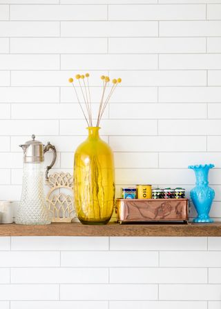 kitchen room with white tiled wall and yelllow vase with flower