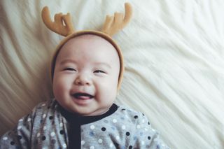 A baby wearing reindeer antlers