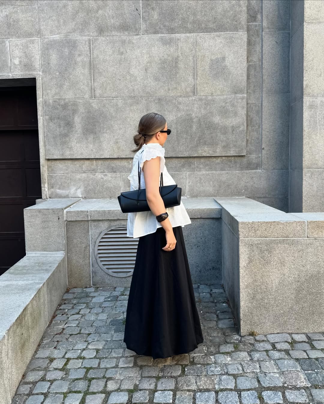@dinahansen wears a black cotton maxi, white ruffle short-sleeve blouse and an east-west shoulder bag