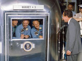 President Richard M. Nixon was in the central Pacific recovery area to welcome the Apollo 11 astronauts aboard the USS Hornet, prime recovery ship for the historic Apollo 11 lunar landing mission. Already confined to the Mobile Quarantine Facility (MQF) are (left to right) Neil A. Armstrong, commander; Michael Collins, command module pilot; and Edwin E. Aldrin Jr., lunar module pilot. Apollo 11 splashed down at 11:49 a.m. (CDT), July 24, 1969, about 812 nautical miles southwest of Hawaii and only 12 nautical miles from the USS Hornet.