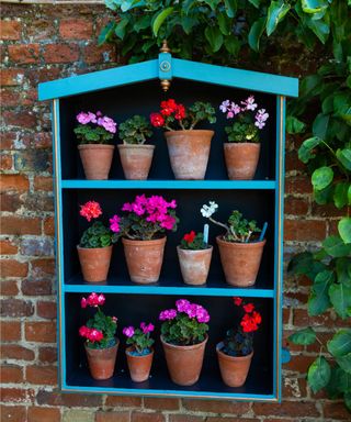 Planter box hanging on a brick wall with brightly colored potted plants