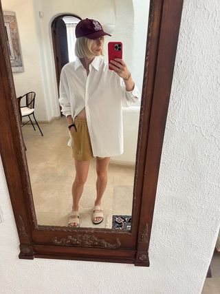 Lara Mead, Da Varley, Vestindo Shorts Bege E Uma Camisa Branca Grande Com Botões E Sandálias Bege.