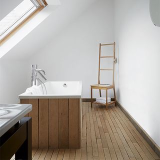 bathroom with white wall and wooden floor and bathtub