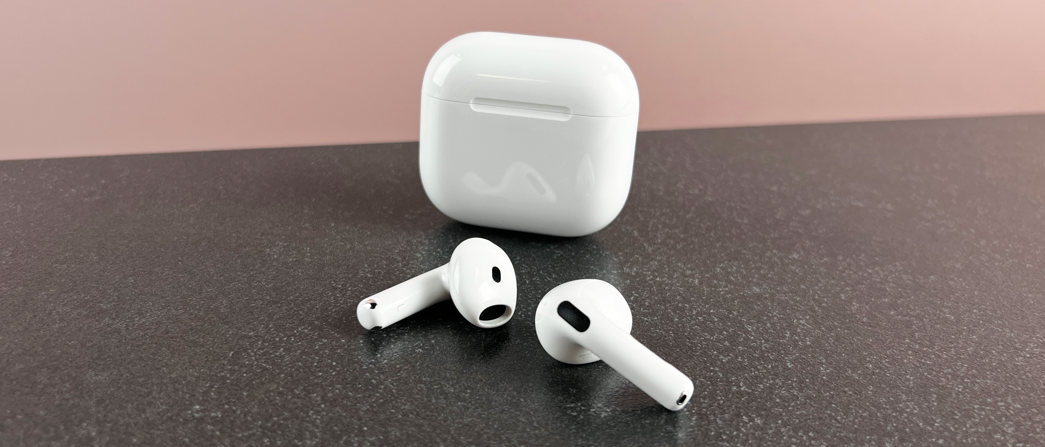 AirPods 4 outside their case on a dark surface