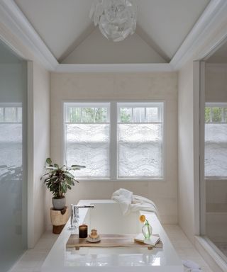 A bathtub in the middle of a bathroom below a circular overhead light fixture