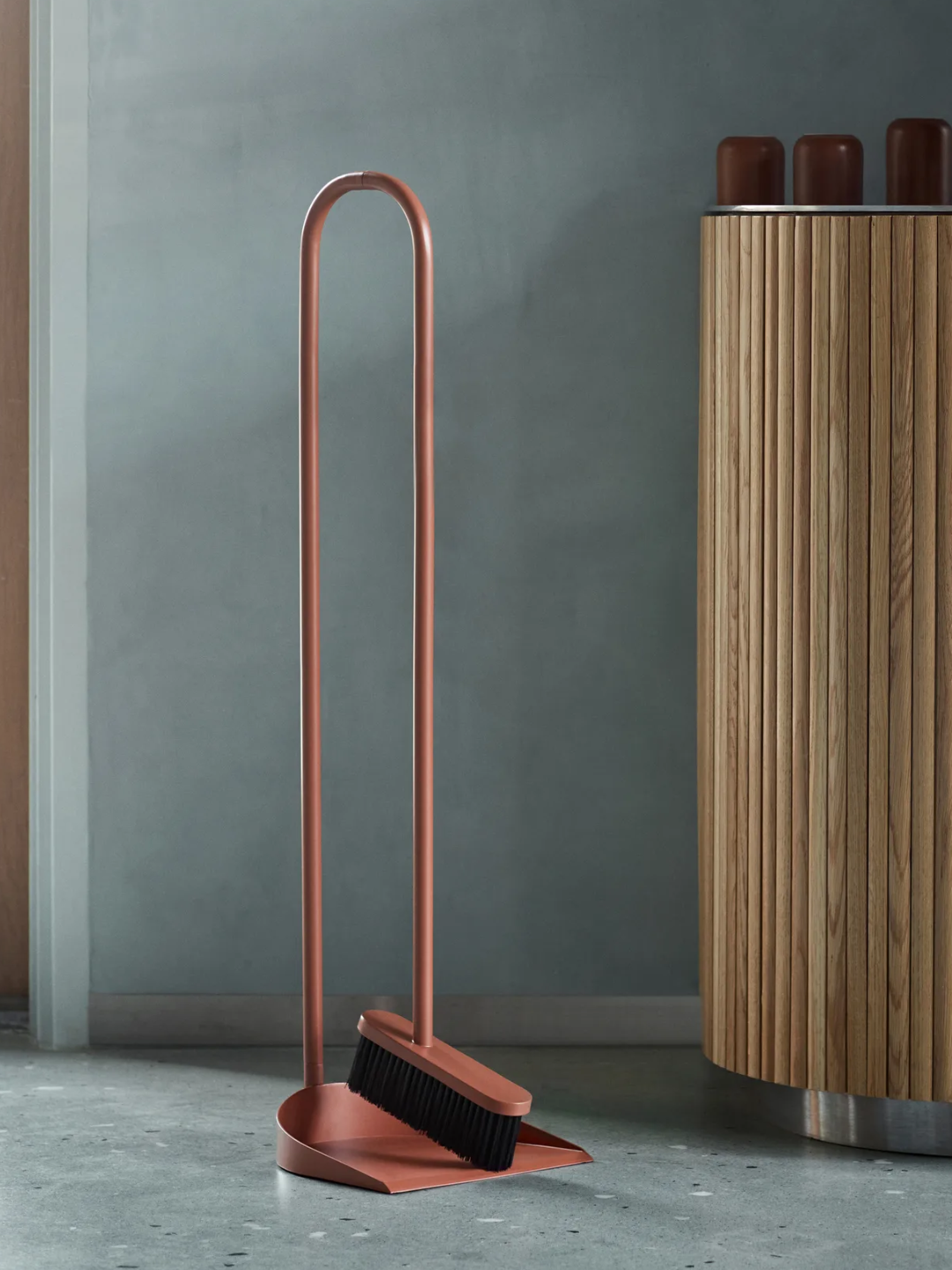 A curved rust-colored cane brush and pan