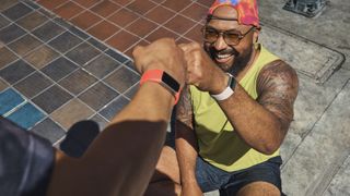 Two athletes wearing Fitbit Charge 6s fist-bump each other