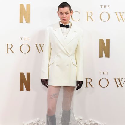 Emma Corrin in a Princess Diana inspired white blazer, bow tie, and sheer skirt by Miu Miu