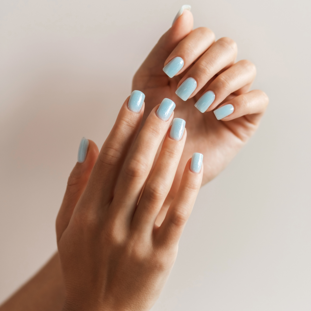 Female hands with beautiful manicure - light blue nails on beige background. Neat female hands after hardware manicure. Manicure, nail, skin care, beauty salon concept.