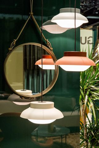 Layered glass and aluminium pendant hanging lamps next to a circle shaped mirror