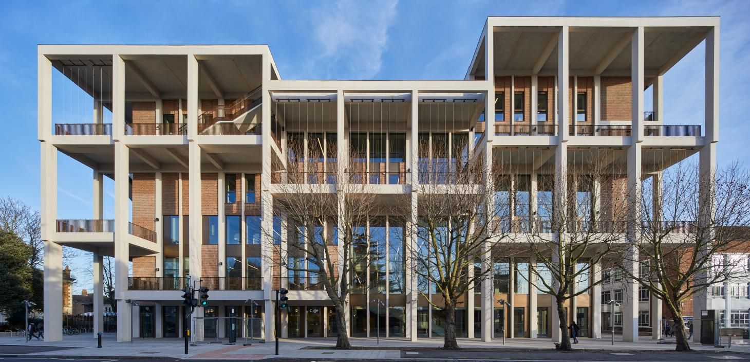 Front look at the Town House. Concrete and red brick facade, with large windows. Concrete columns at the front of the building support large terraces.
