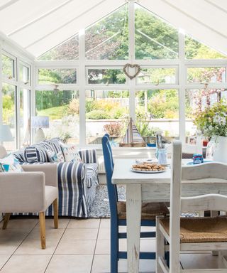 Conservatory with wrap-around glass windows in nautical theme and whitewashed furniture