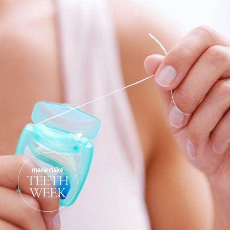 a close up of a woman's manicured hands pulling floss out of a mint green plastic container
