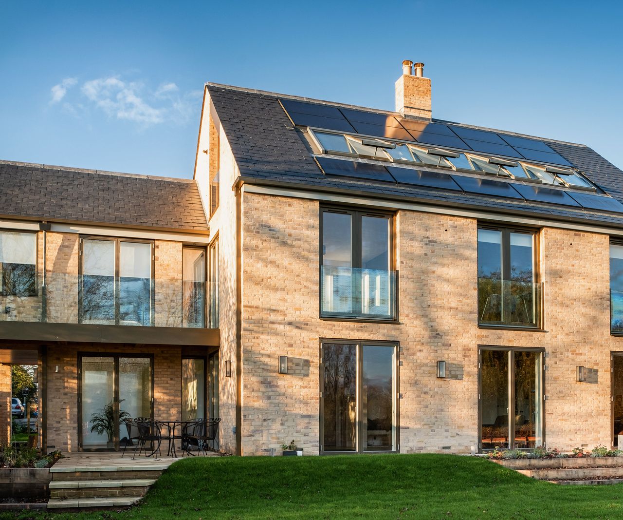 A self build home with brick cladding and a pitched roof with a row of roof glazing and solar panels