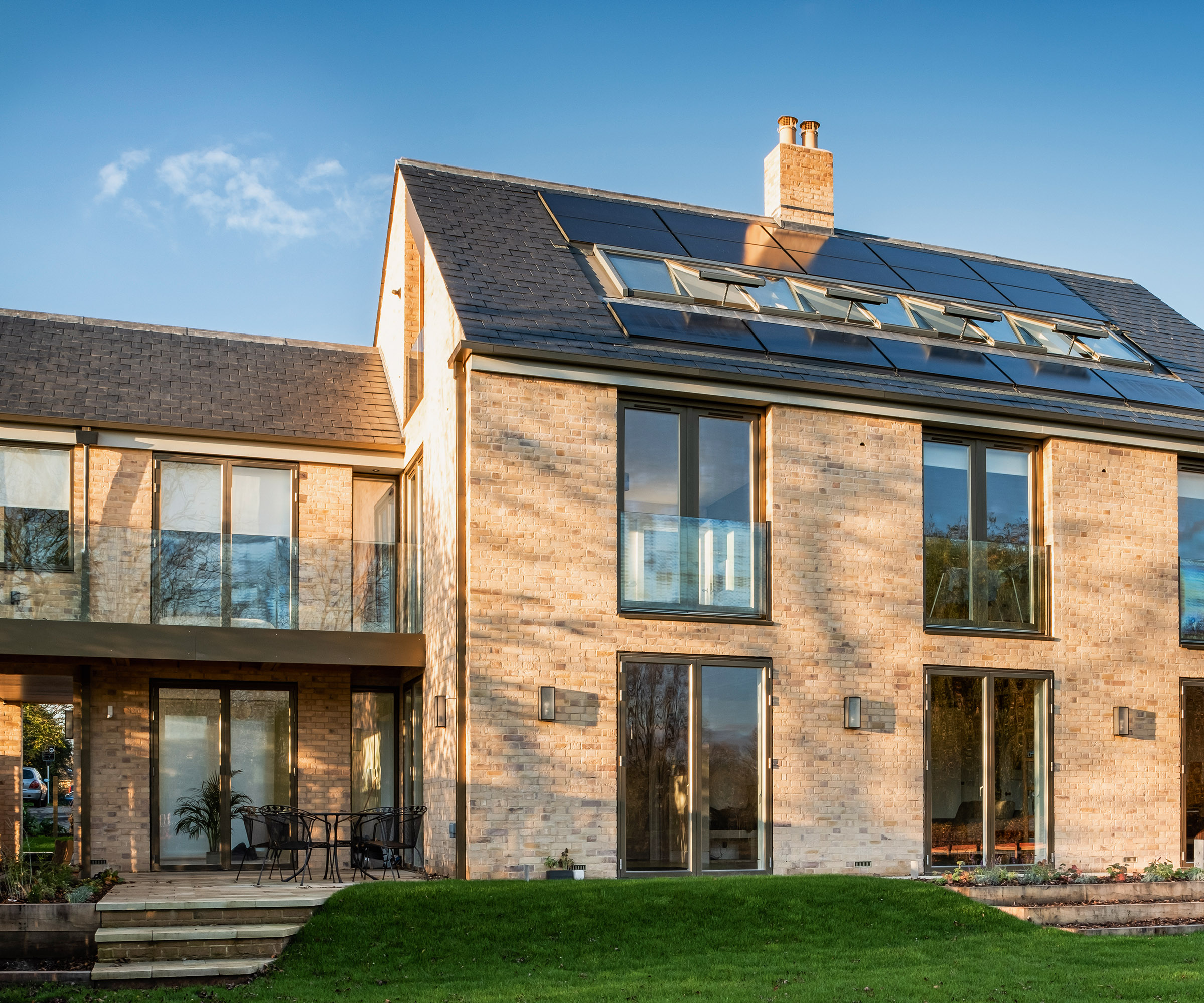 A self build home with brick cladding and a pitched roof with a row of roof glazing and solar panels