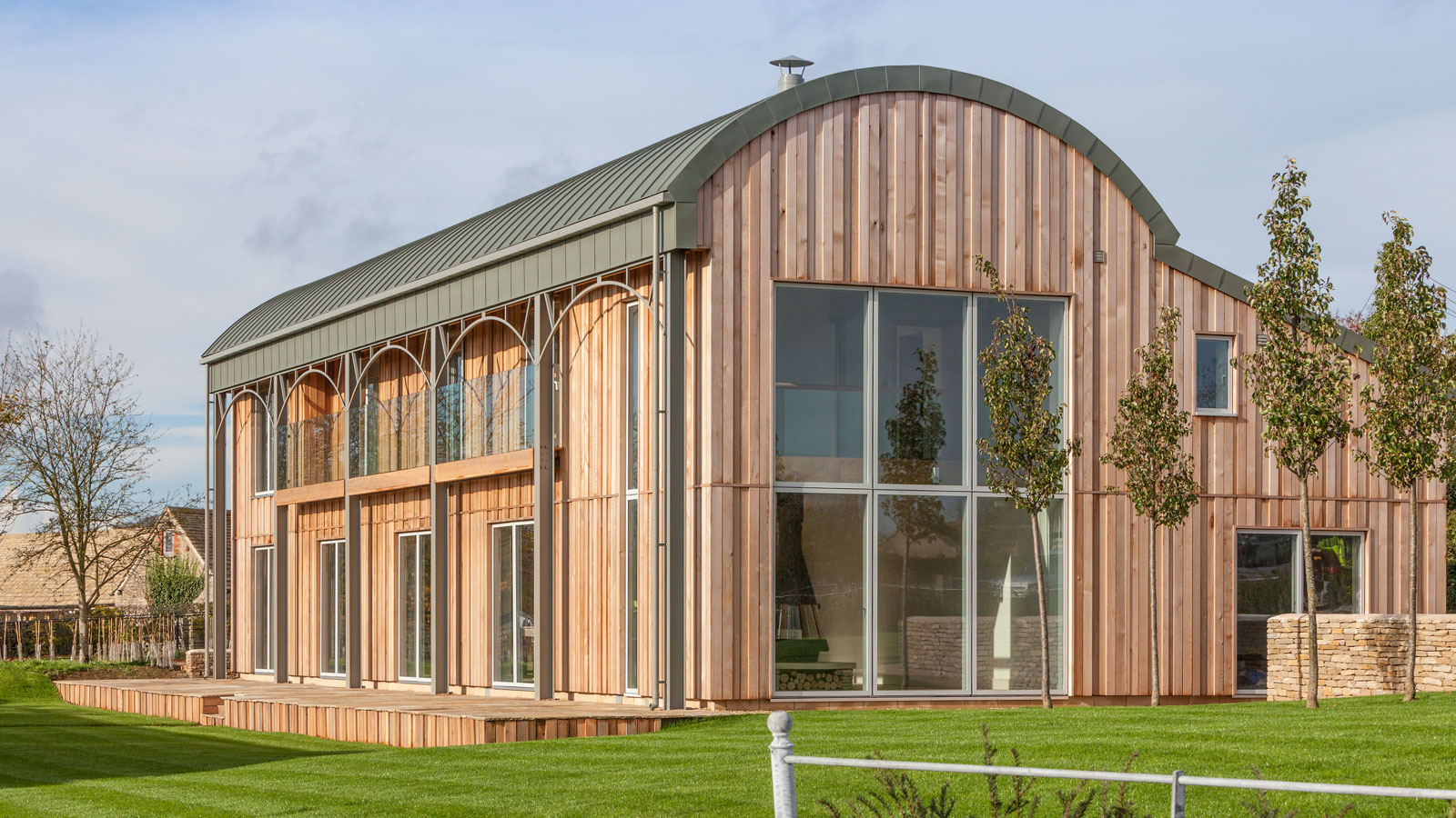 timber clad Dutch barn conversion with full height glazing and curved metal roof