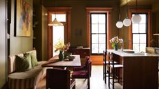 An olive green kitchen with a wood island and a striped banquette seating area
