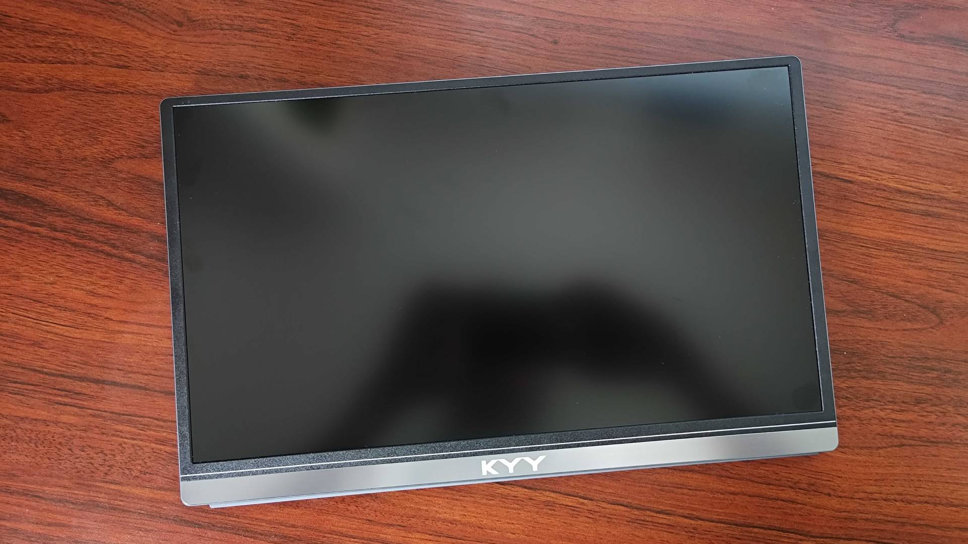 KYY K3 Portable monitor lying on woodgrain desk facing upwards.