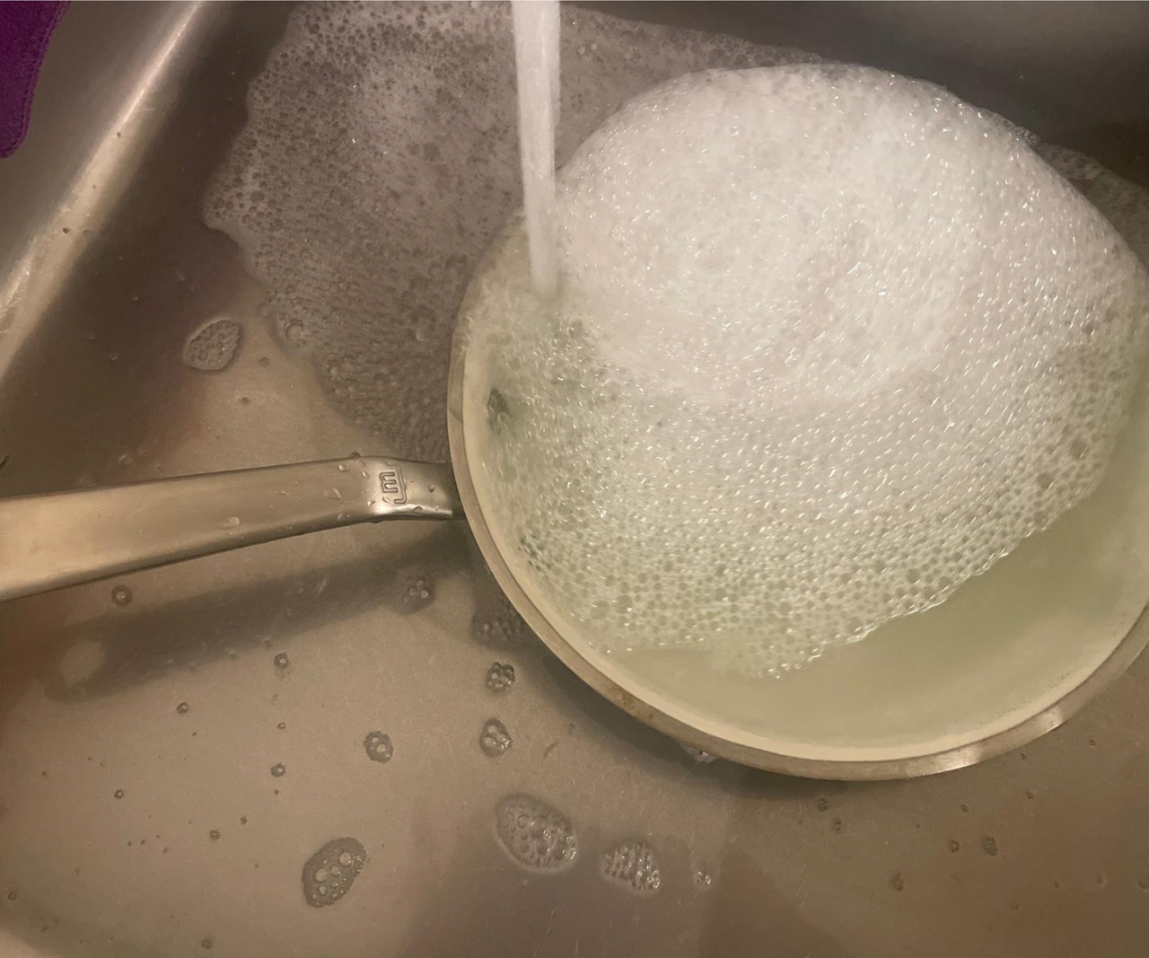 Made In CeramiClad&trade; Non-Stick Frying Pan in a stainless steel sink being filled with soapy water