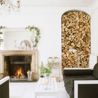 fireplace with white wall and firewood