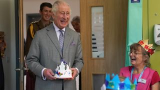 King Charles III holding a crown gifted by four-year-old Arielle Bayliss who's mother Rebecca Turner (centre) is a patient whilst opening the Priscilla Bacon Lodge hospice, a state-of-the-art palliative care unit which has been specially designed to allow patients to enjoy the surrounding landscape, working in partnership with Norfolk Community Health and Care NHS Trust on October 26, 2023 in Norwich, England.