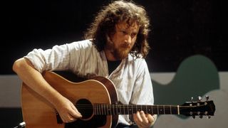 John Renbourn performs on an acoustic guitar