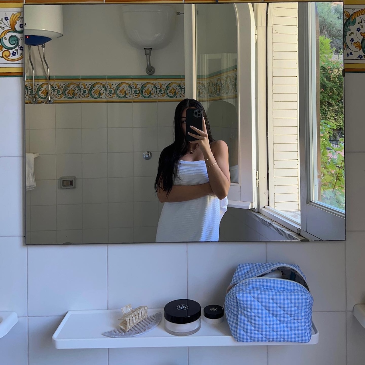 A woman wearing a bath towel and taking a mirror selfie