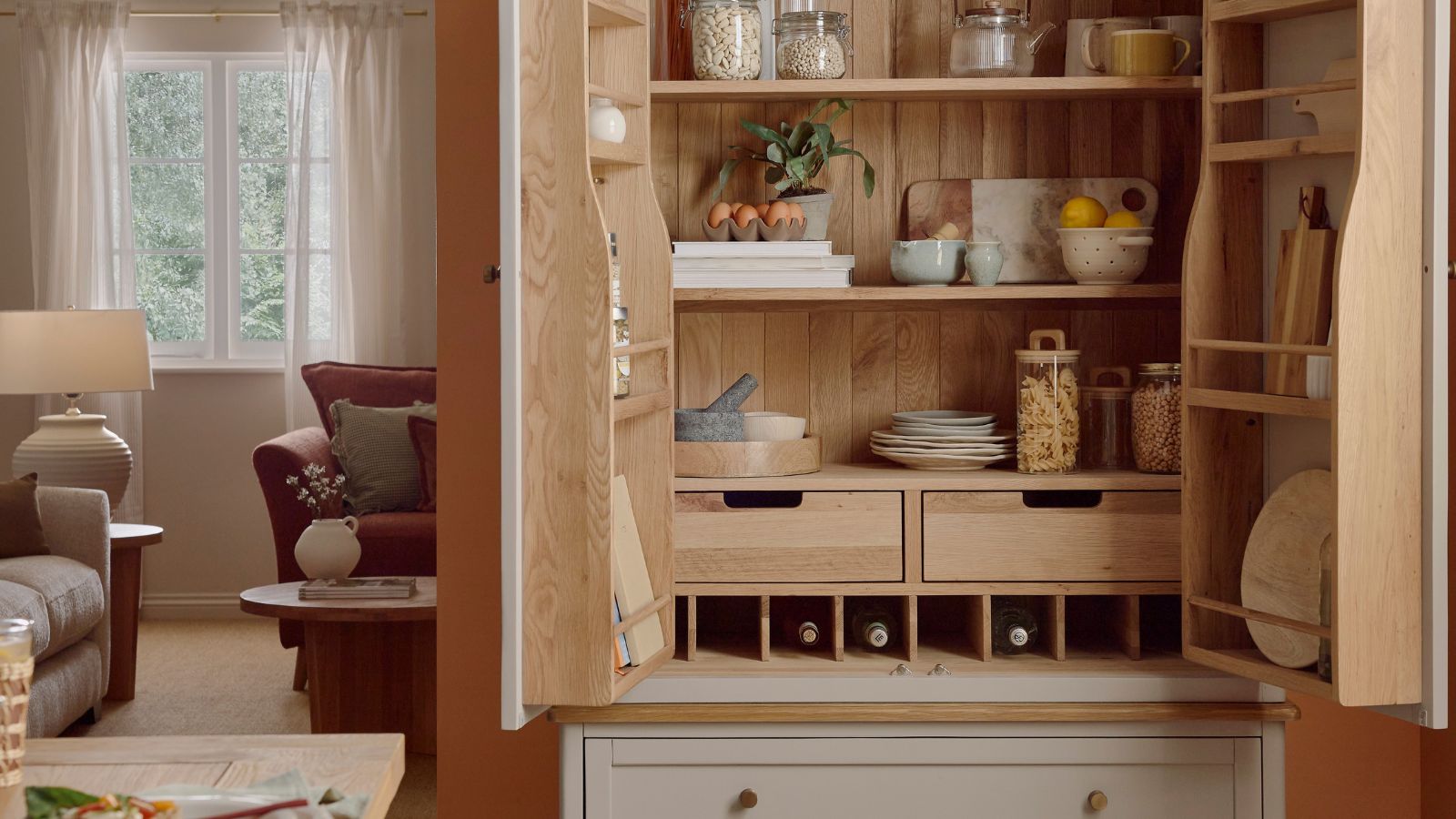 Warm, handcrafted pantry cupboard in natural oak, featuring open shelves, drawers, wine storage, and curated ceramics for a cosy, organised feel.