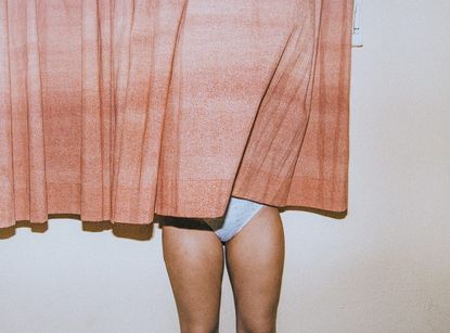 Is vaginal discharge normal? A woman stands behind a curtain