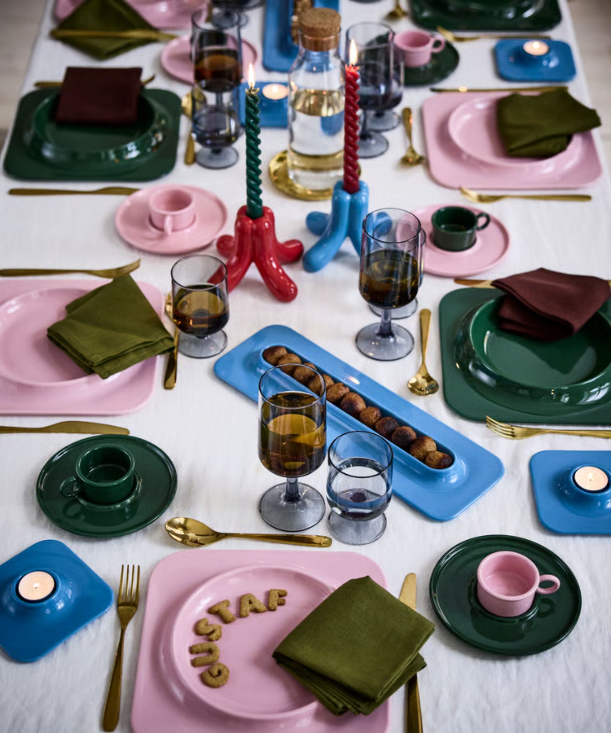 christmas table laid with the Gustaf Westman x IKEA collection with pink blue and dark green colors and sculptural candle holders and twisted taper candles