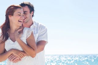 A young couple laughs together on a beach