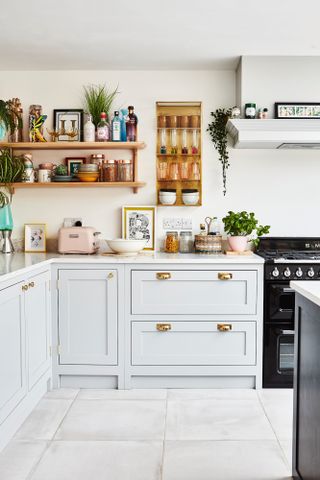 Neutral grey Shaker-style kitchen with white marble worktop, open wood shelving, grey large format floor tiles