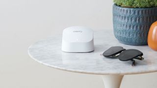 Amazon Eero 6 Mesh Wi-Fi 6 on marble side table next to sunglasses and blue planter